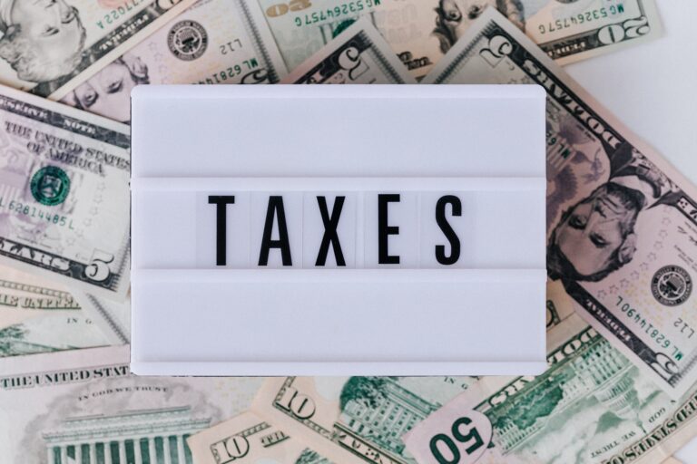Sign that reads taxes with money in the background.