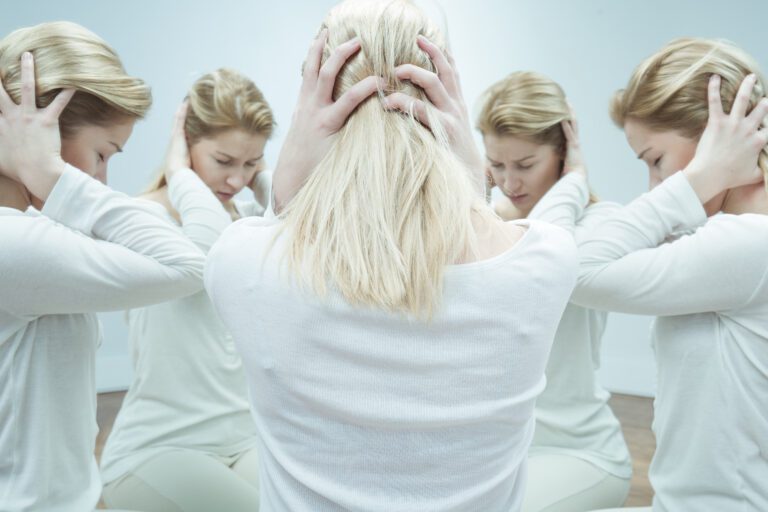 Many women holding ears in a circle looking inwards with their head down.