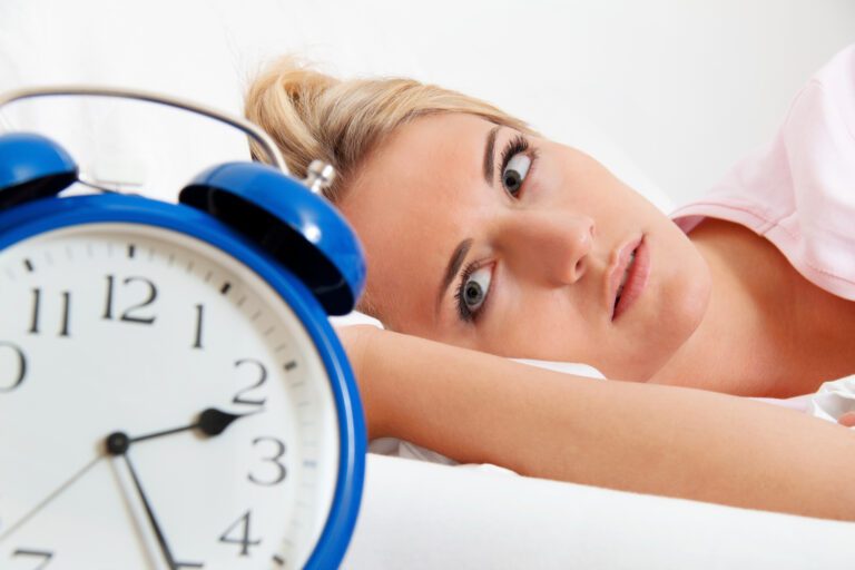 Woman in bed looking at clock.