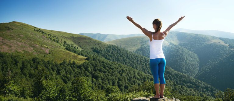 Young woman outstretched arms on a mountaintop.