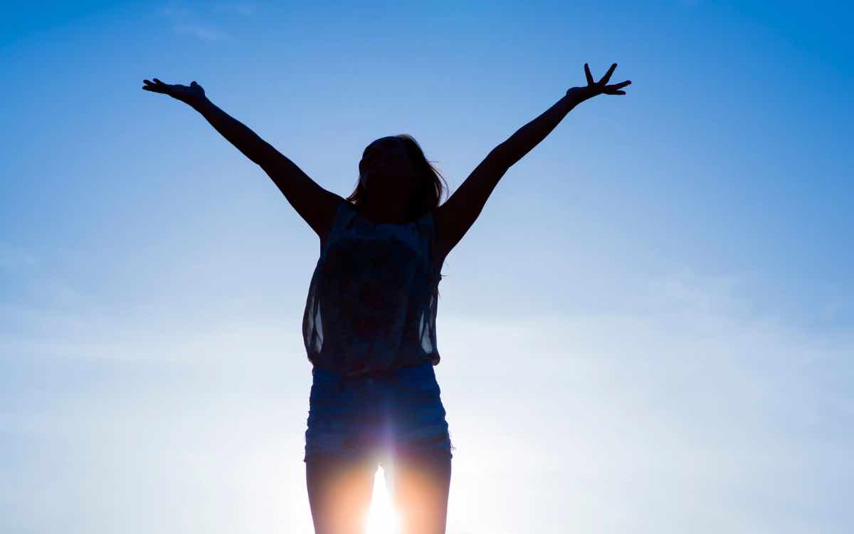 woman raising arms to sky